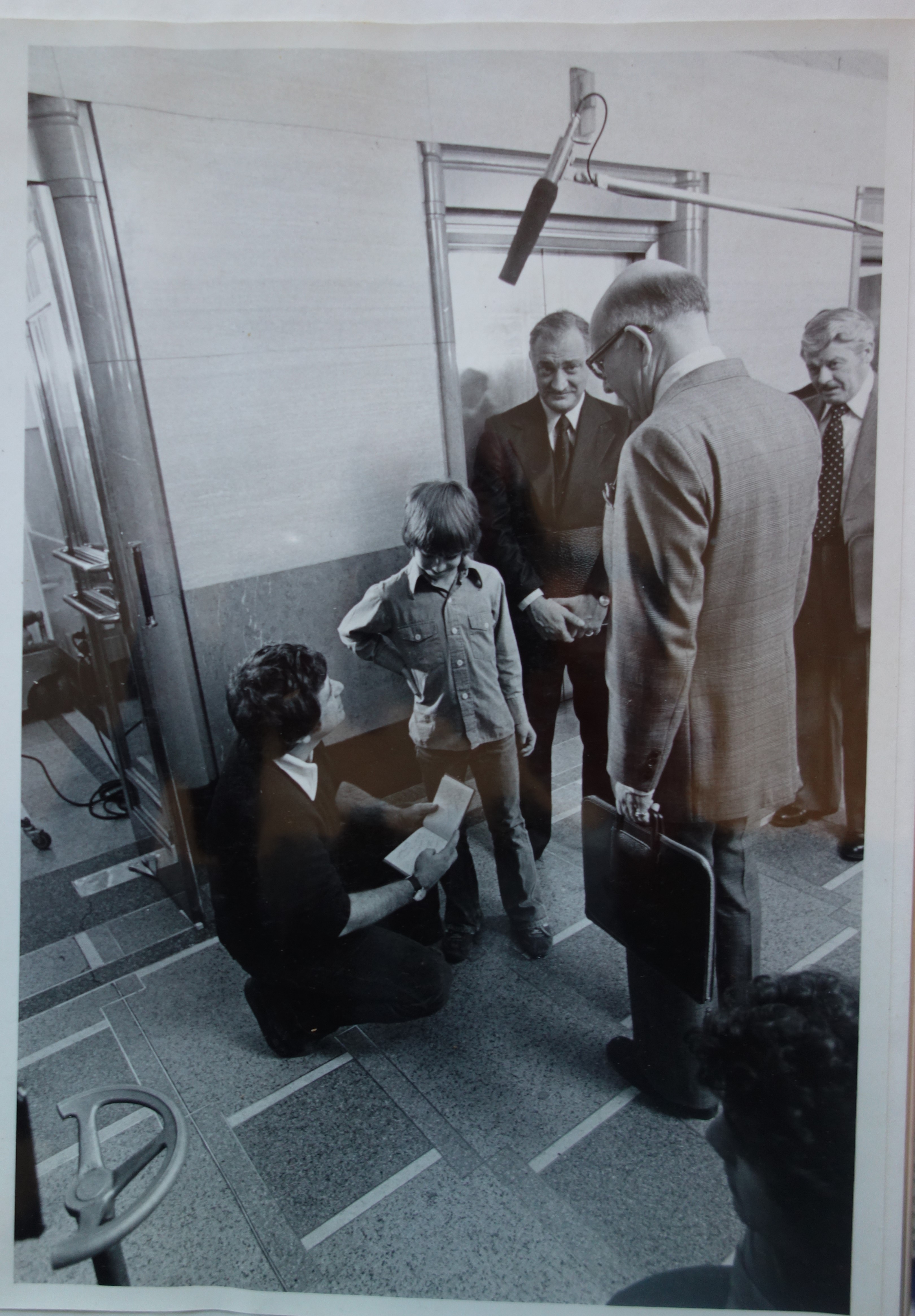 Figure 4: Production still from The Tar Sands featuring director Peter Pearson (crouching in foreground), Mavor Moore (with glasses and his back to the camera) in character as Frank Spragins, President of Syncrude Canada Ltd., and George Touliatos as oil company representative David Bromley.