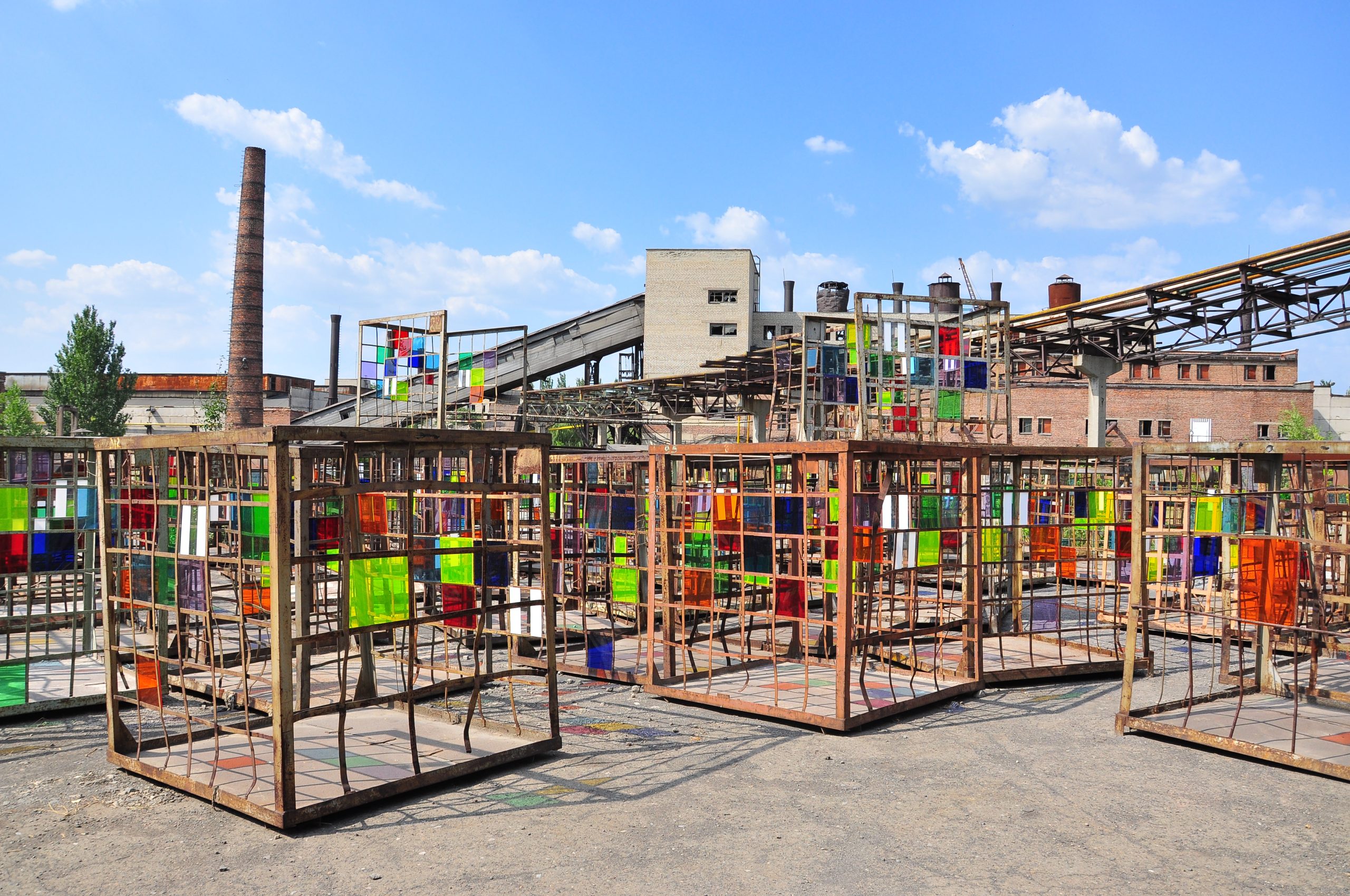 art installation of metal cubes with colored glass plates in the courtyard of a defunct factory